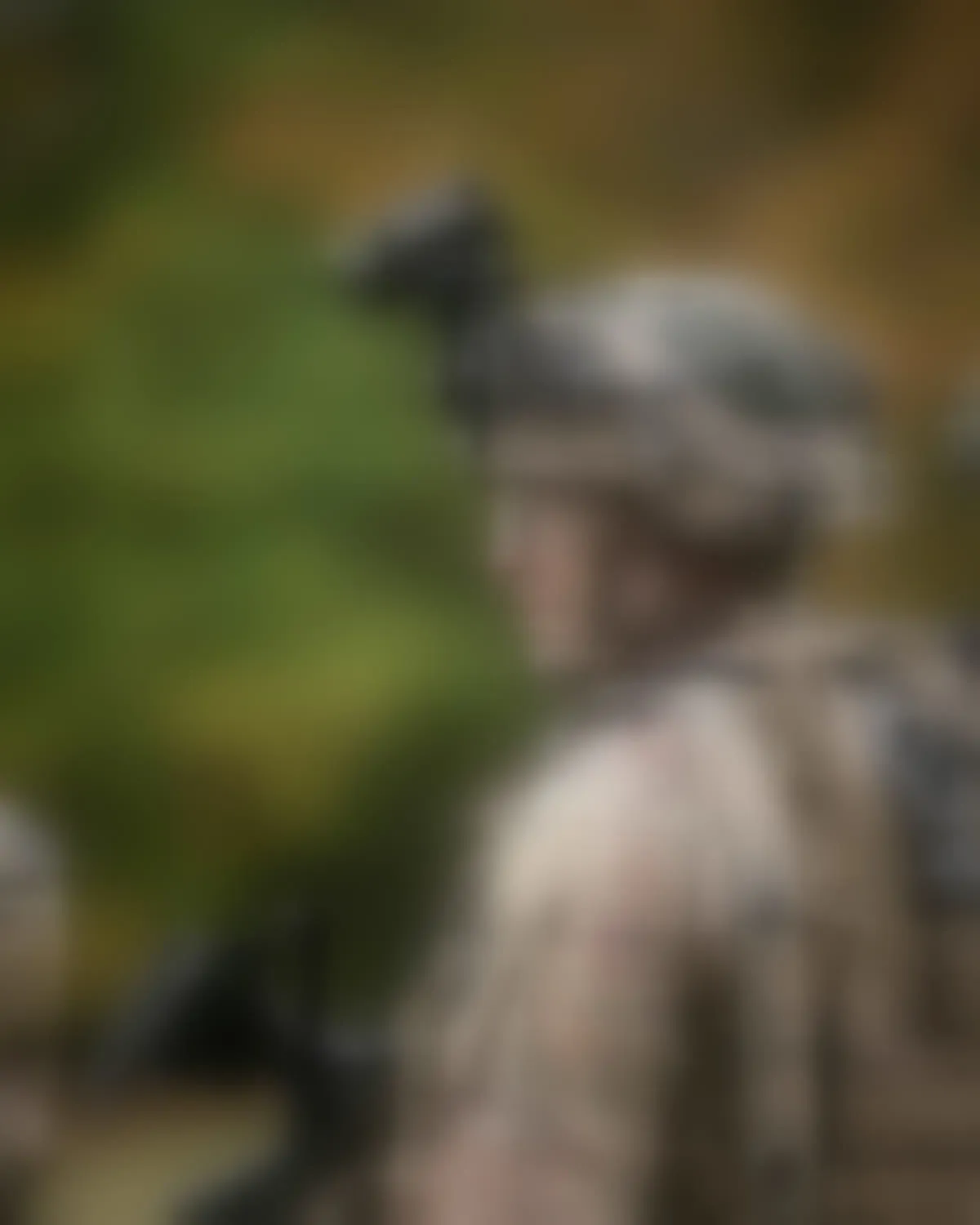 A person in helmet and body armour, seen in profile and deliberately blurred.